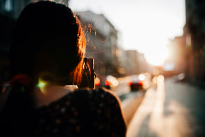 Rear view of mid adult woman photographing while standing on road in city