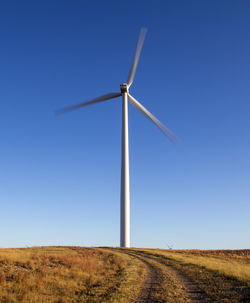 Wind turbine in motion against blue sky