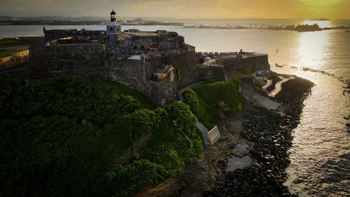 High angle view of sea and buildings against sky at sunset