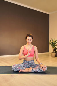 Young woman doing yoga on yoga mat in atmospheric yoga studio