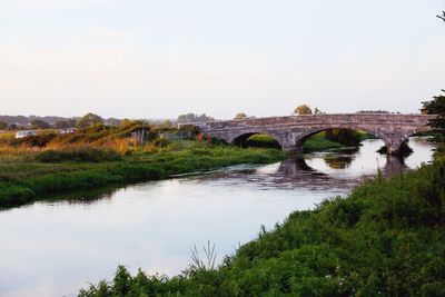 Arch bridge over river against sky