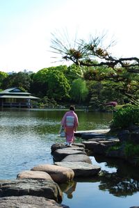 Rear view of woman in traditional clothing walking on stepping stones at park