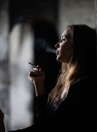 Young woman looking away while standing against wall