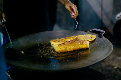 Cropped hands preparing food on pan