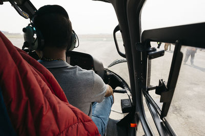 Rear view of man sitting in helicopter