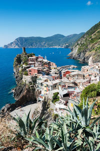 High angle view of town by sea against clear blue sky