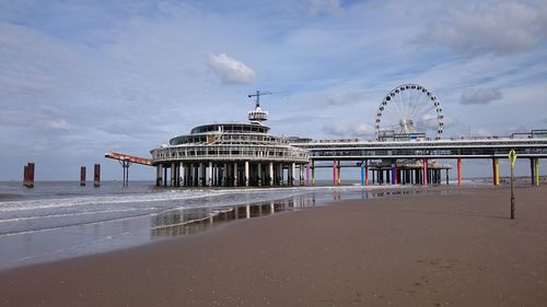 View of pier on beach against cloudy sky