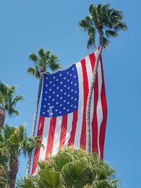 Low angle view of flags against clear blue sky