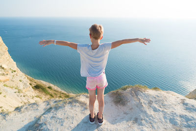 Full length rear view of man standing by sea