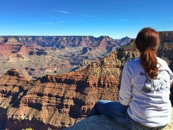 Rear view of looking at grand canyon national park while sitting on cliff