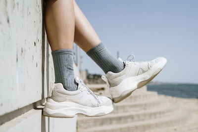 Mid adult woman dangling feet while sitting on retaining wall