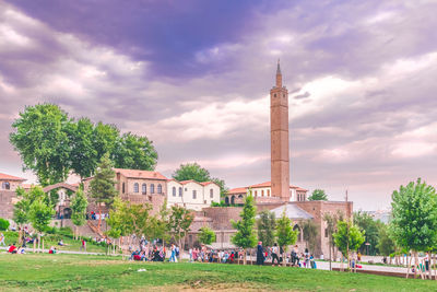 Group of people in front of building against cloudy sky