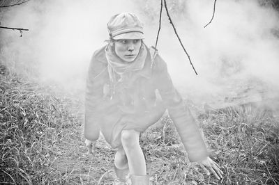 A girl sneaks on the grass in the dense smoke