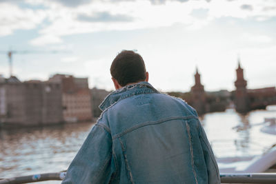 Rear view of man looking at river in city