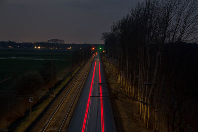 Light trails on road against sky at night