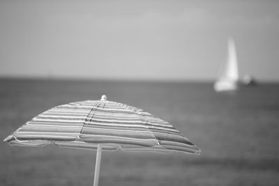 Close-up of parasol on beach against sky