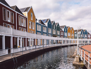 Buildings by river against sky