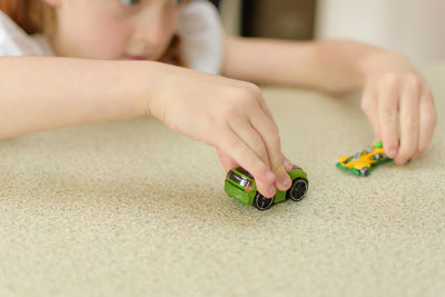 Close-up of girl playing with toy cars at table