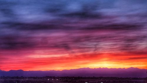 Scenic view of dramatic sky over silhouette landscape during sunset