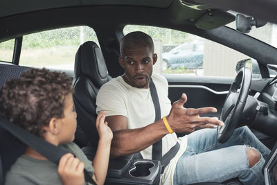 Boy talking with father while sitting in electric car