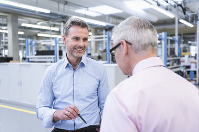 Two mangers discussing on shop floor of company