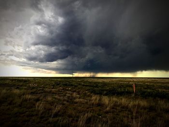 Scenic view of field against storm clouds