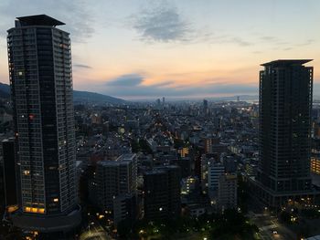 Aerial view of modern buildings against sky at sunset