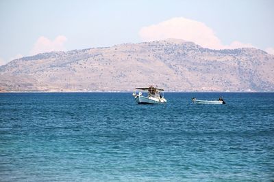 Boat sailing on sea against mountains