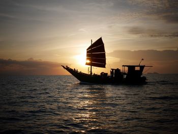 Silhouette ship sailing on sea against sky during sunset