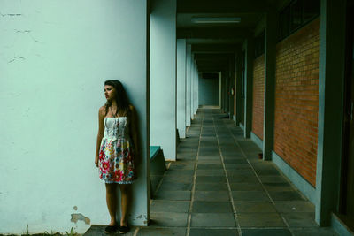 Thoughtful young woman leaning on wall in building