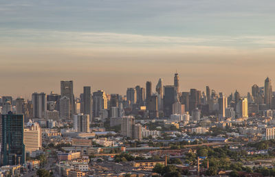 Modern buildings in city against sky during sunset