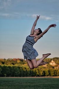 Midsection of woman jumping against the sky