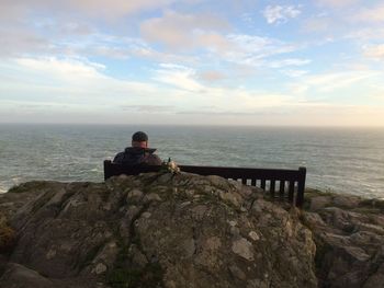 Rear view of man on bench against sea