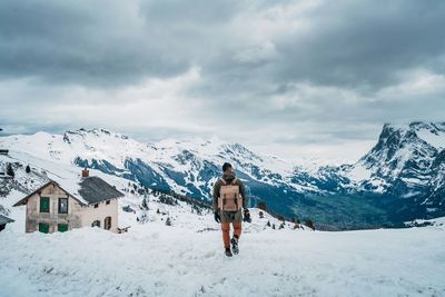 Rear view of person on snowcapped mountain against sky