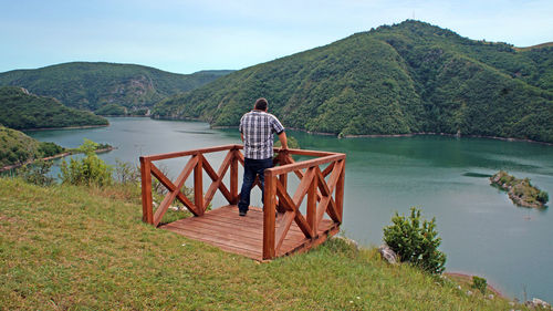 Rear view of man standing at observation point against mountains