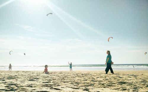 People flying over beach against sky