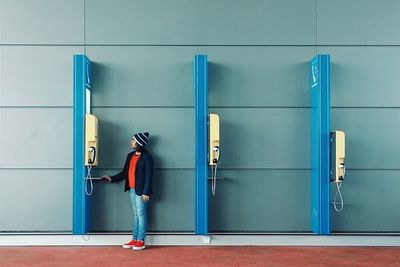 Portrait of boy standing by pay phone