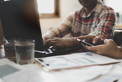 Midsection of man using mobile phone while sitting on table