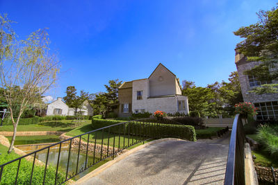 House by trees and buildings against blue sky
