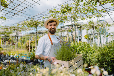 Portrait of young man standing in greenhouse