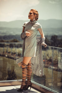 Young woman looking away while standing on railing