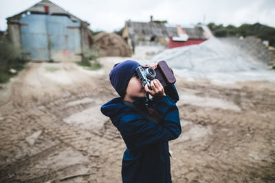 Boy photographing while standing on land