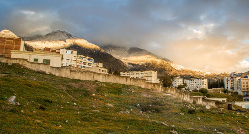 Buildings by mountain against sky