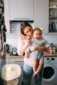 Mom feeds a small child at home with yogurt from a spoon. family concept