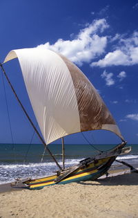 Sailboat moored at beach against sky