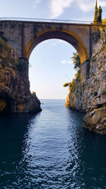 Arch bridge over sea against sky