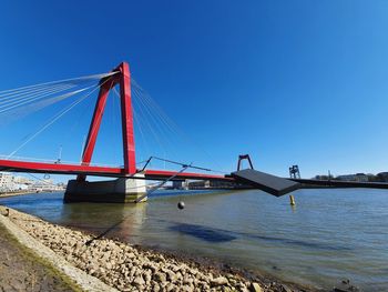 Suspension bridge over sea against clear blue sky