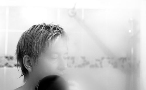 Close-up of man standing behind shower glass in bathroom