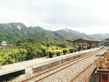 Railroad tracks by mountain against sky