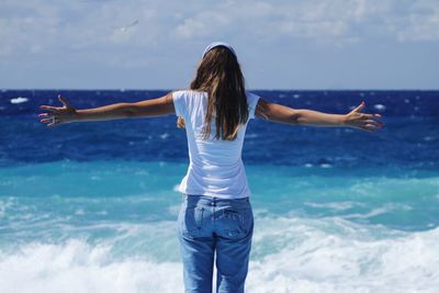 Rear view of woman standing against sea at beach